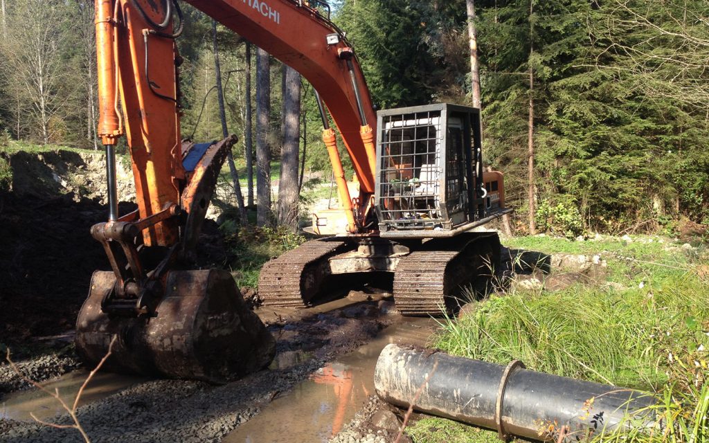 excavator prepping for drainage on a access road build